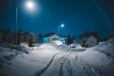 晚上，蓝色天空下的雪地上有一座棕色和白色的房子